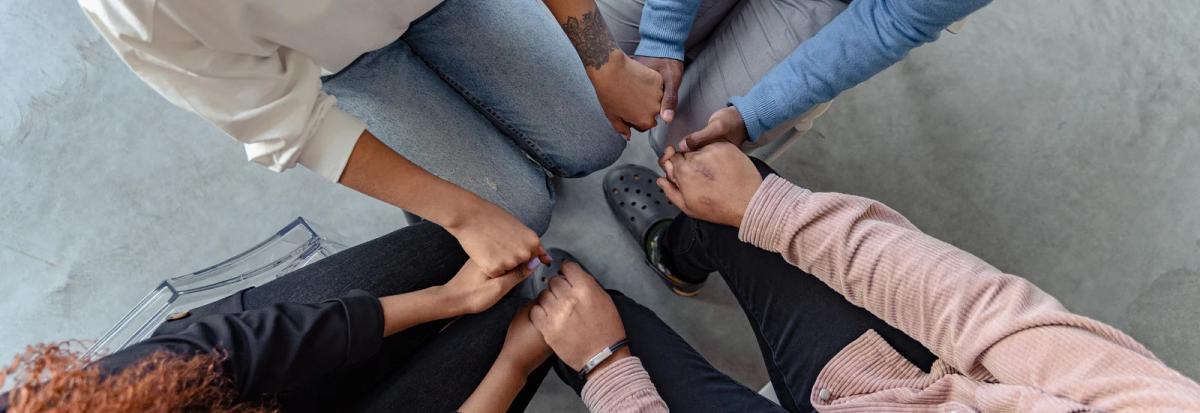 A support group sitting in a circle holding hands